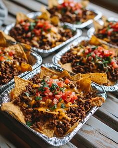 several trays filled with nachos and salsa on top of a wooden table