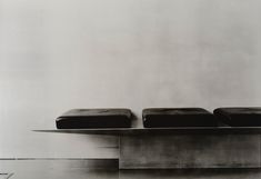 black and white photograph of three stools on top of each other in front of a wall