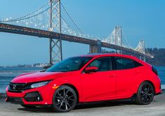 a red honda civic is parked in front of the bay bridge