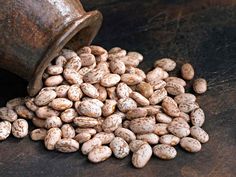 a pile of peanuts sitting on top of a wooden table next to a metal container