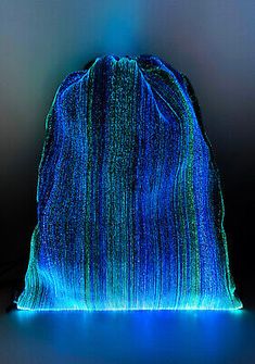 an illuminated bag sitting on top of a black table next to a blue and green light