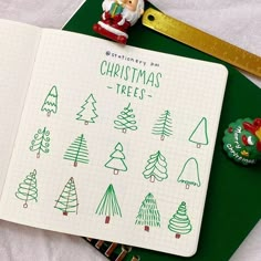 an open notebook with christmas trees drawn on it next to a pencil and rubber ruler