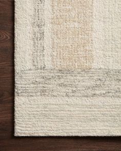 a white rug on top of a wooden floor next to a brown and white wall