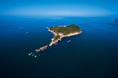 an island in the middle of the ocean surrounded by land and blue water with boats