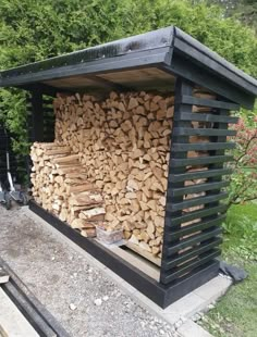 a large pile of wood sitting on top of a wooden bench next to a forest