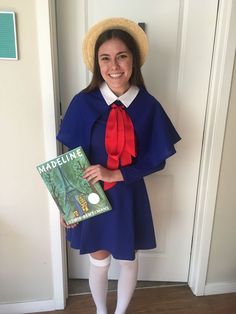 a woman wearing a blue dress and red tie holding a book while standing in front of a door