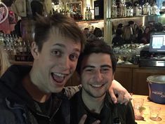 two men posing for the camera at a bar