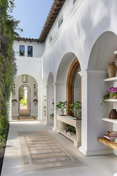 a white house with arched doorways and potted plants on the side walk way