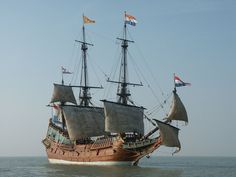 an old sailing ship in the ocean with flags flying from it's masts