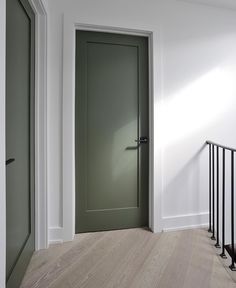 an empty room with a green door and railing