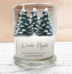 a candle that is sitting on a table with some trees in the middle of it