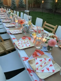 a long table is set with place settings and candles for an outdoor dinner or party