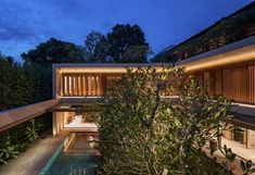 an exterior view of a modern house with pool and trees in the foreground at night