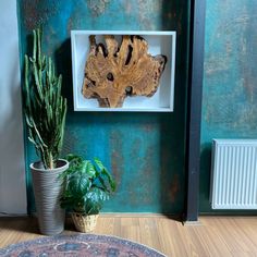 a potted plant sitting next to a wooden piece of art on a green wall