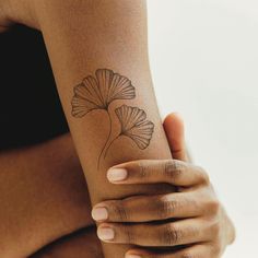 a woman's arm with a flower tattoo on the left side of her arm