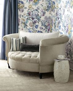 a living room with floral wallpaper and a chair in front of the window,