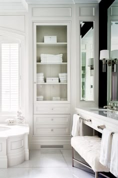 a white bathroom with a tub, sink and large mirror on the wall next to it