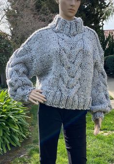 a mannequin wearing a gray sweater and black pants in front of a house