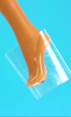 an orange foot sticking out of a clear plastic container on top of a blue surface