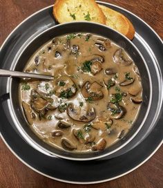 a bowl of mushroom soup with bread on the side