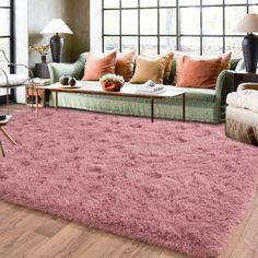 a living room filled with furniture and a pink rug on top of a hard wood floor