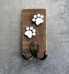 an animal paw print is mounted on a wooden doorknob with metal hooks