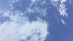 an airplane is flying high in the blue sky with white clouds and some green trees