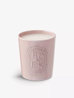 a pink candle with the words roses on it and an oval logo in white lettering