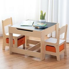 a wooden table with two chairs and an open book on the top, in front of a window