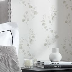 a nightstand with two books and a vase on it