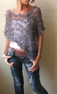 a woman standing with her hands on her hips wearing ripped jeans and a short sleeved top