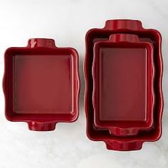 two red trays sitting next to each other on a white counter top with one empty