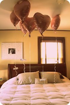 a bed with balloons hanging from it's headboard and pillows on top of it