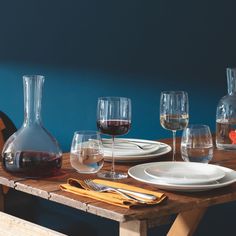 a wooden table topped with wine glasses and plates