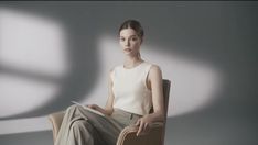 a woman is sitting in a chair and looking at the camera while holding a book