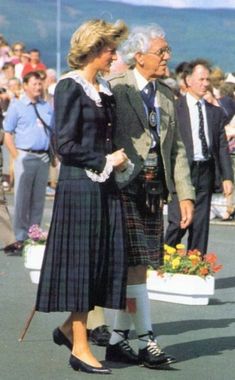 an older man and woman standing next to each other in front of a group of people