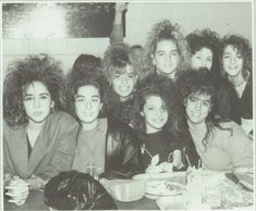 a group of young women sitting at a table with food and drinks in front of them