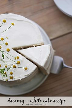 a cake with white frosting and yellow flowers on it sitting on top of a plate