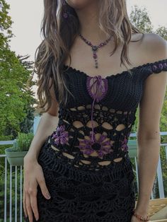 a woman wearing a black crochet top with purple flowers