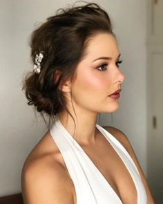 a woman wearing a white dress with a flower in her hair is looking off to the side