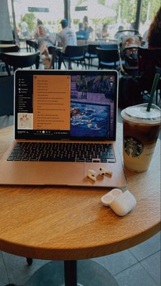 an open laptop computer sitting on top of a wooden table next to a cup of coffee