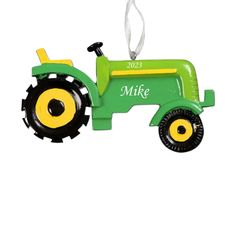 a green and yellow tractor ornament hanging on a white wall with the name mike