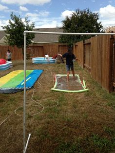 a young boy standing on top of a wet paddling in a backyard next to a fence