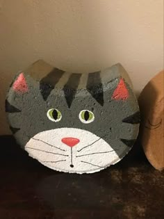 a painted rock with a cat's face on it