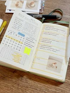 an open book sitting on top of a wooden table next to a pen and glasses