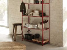 a red shelving unit with pots and pans on it in a living room