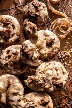 several donuts with icing and nuts on a cooling rack