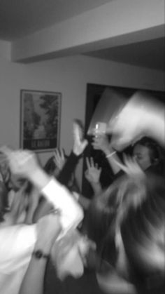 a group of people standing around each other in a living room with their arms up