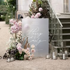 a wedding sign with flowers and candles in front of the entrance to an old building