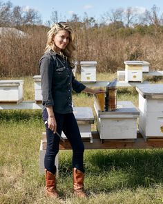 a woman standing in front of some beehives